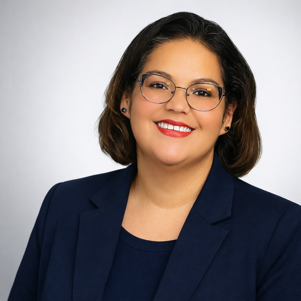 Foto profesional de una terapeuta latina con lentes y traje azul marino, sonriendo con calidez y confianza. Representa a una psicóloga o consejera hispana bilingüe especializada en salud mental para la comunidad latina en Oklahoma City. Servicios de terapia en español, apoyo emocional y consejería para hispanos e inmigrantes en Oklahoma, ofrecidos por una profesional de salud mental culturalmente competente.